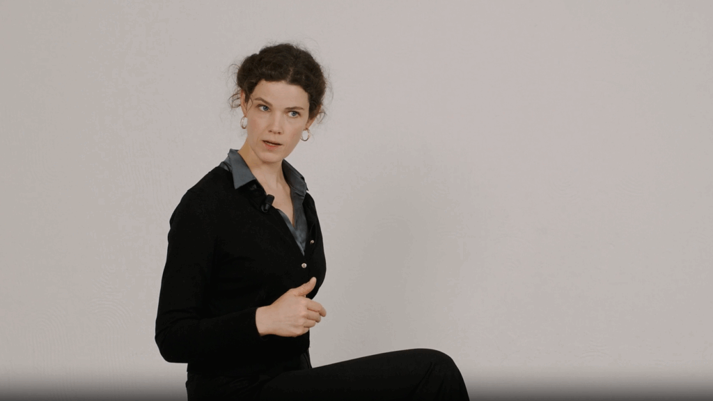 Teresa erklärt auf einem Hocker sitzend